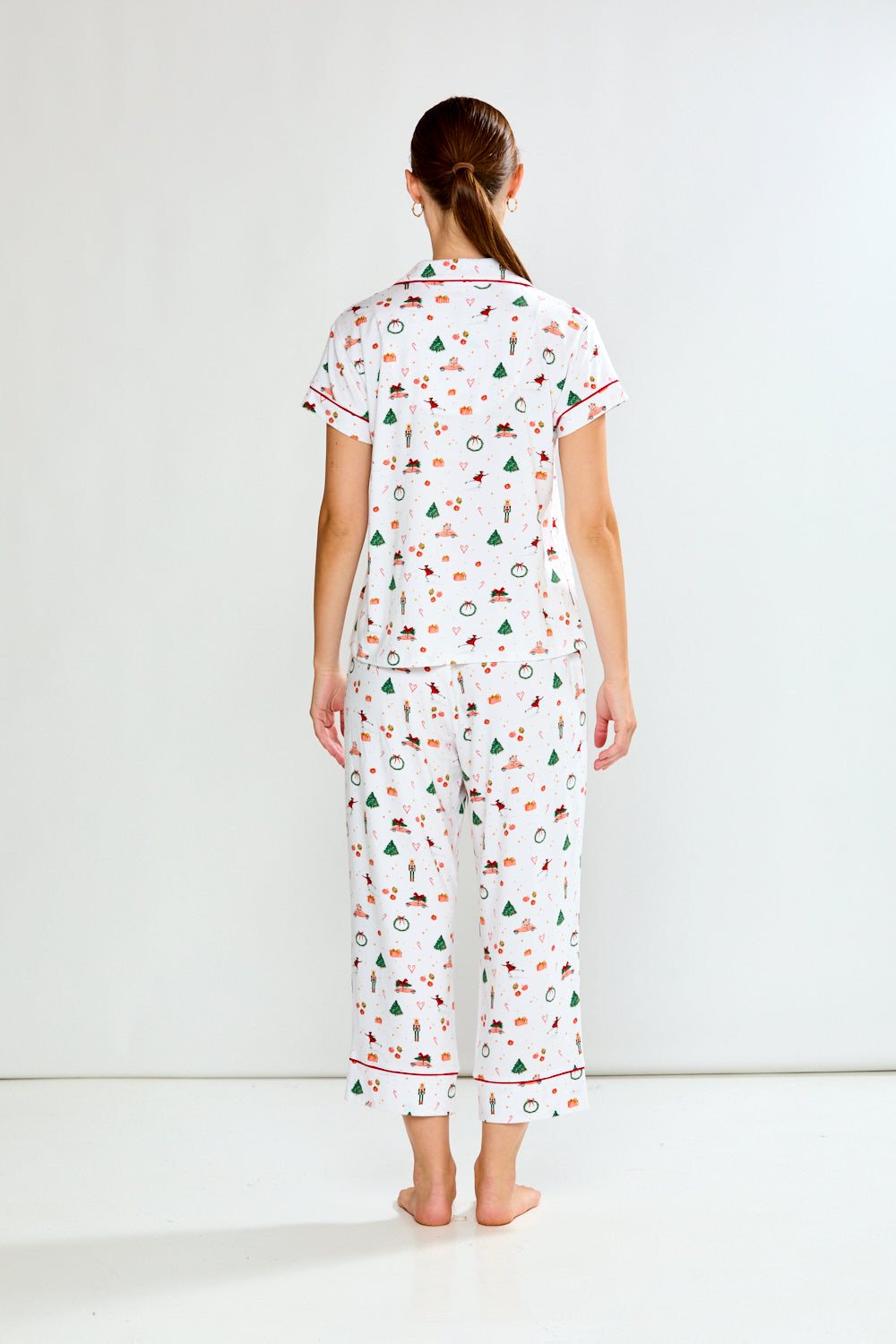 Woman wearing a white pajama set with colorful patterns on a white background
