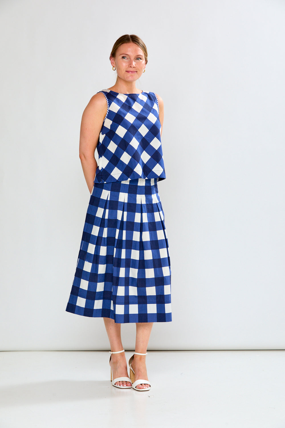 Woman wearing a blue and white checkered dress against a white background