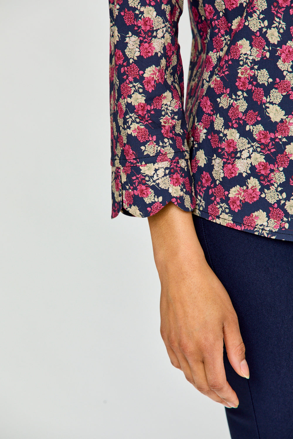 Woman wearing a floral shirt and dark pants on a white background