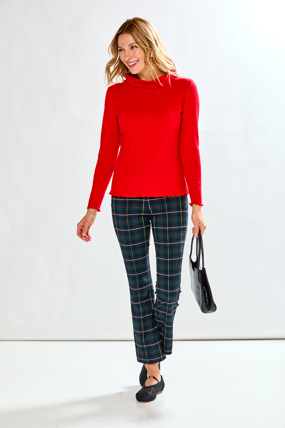 Woman wearing a red sweater and plaid pants on a white background