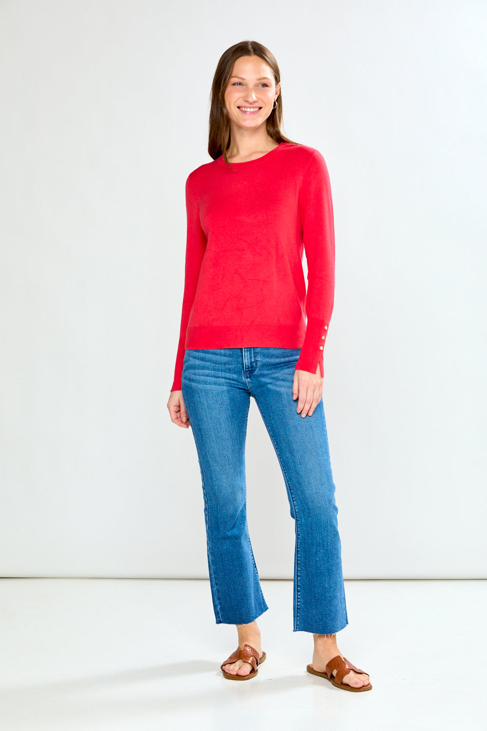 Woman wearing a pink sweater and light blue jeans on a white background