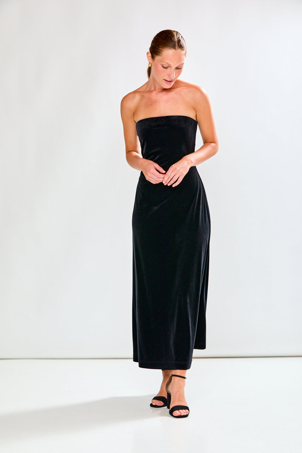 Woman wearing a black strapless dress against a white background