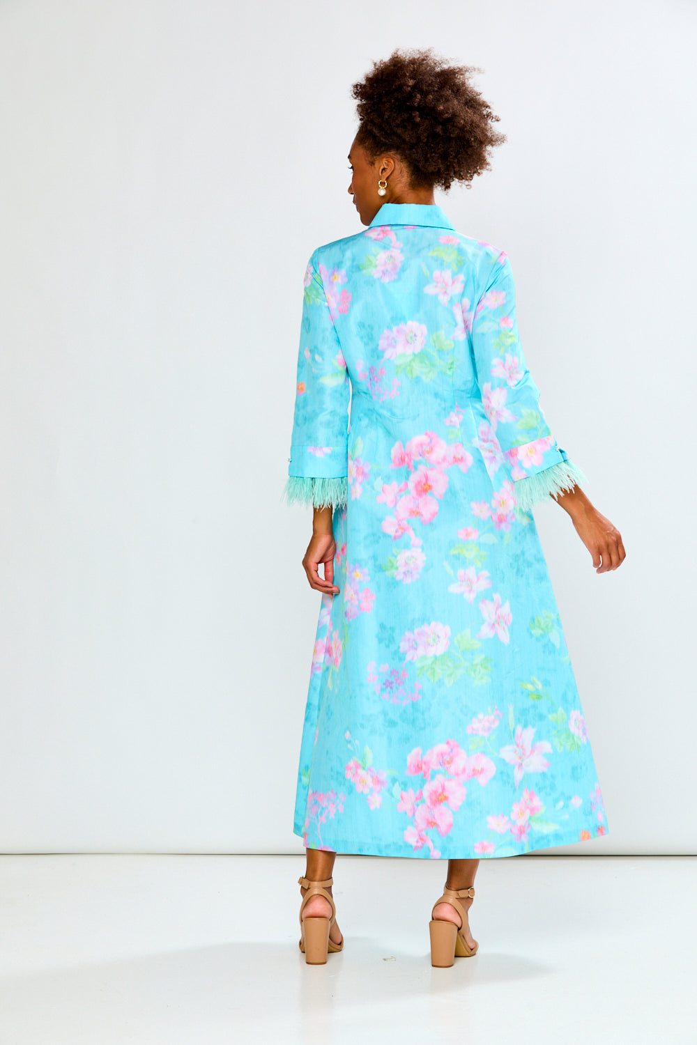 Woman wearing a light blue floral dress against a white background