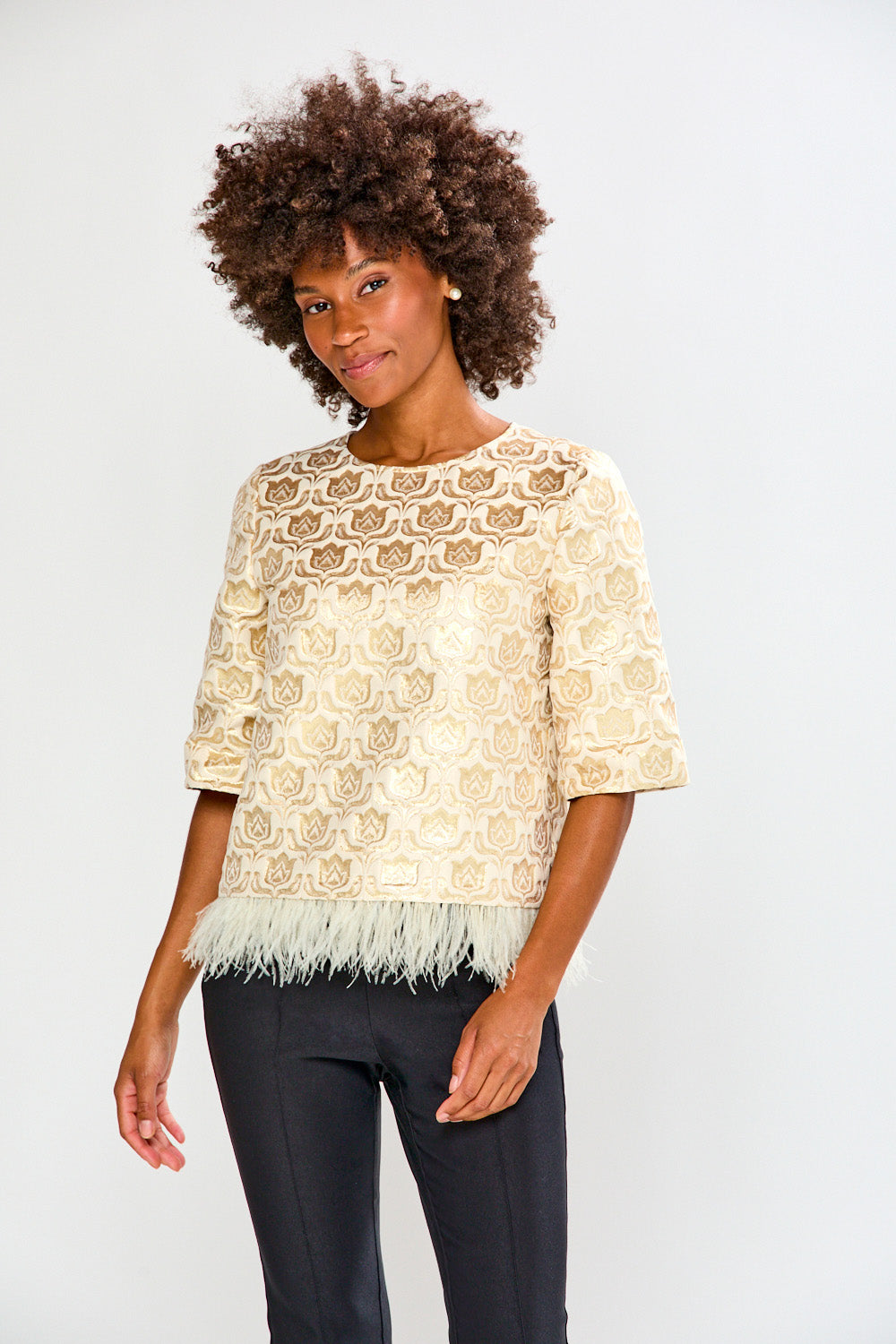 Woman wearing a beige lace top with feather details on a white background
