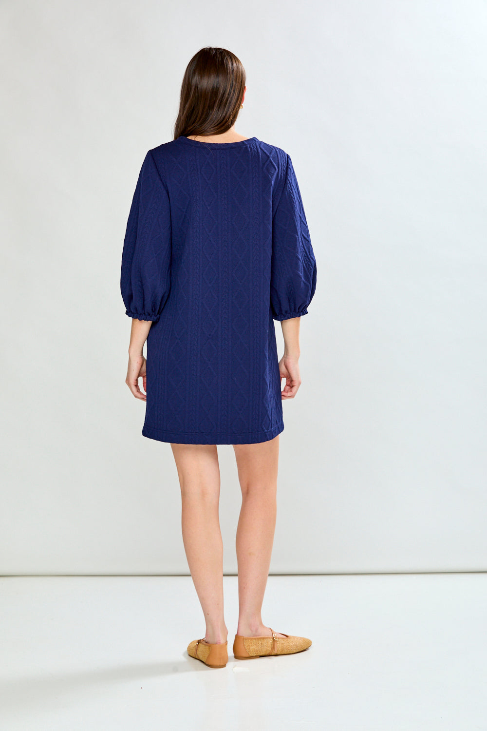 Woman wearing a blue dress with puffed sleeves on a white background