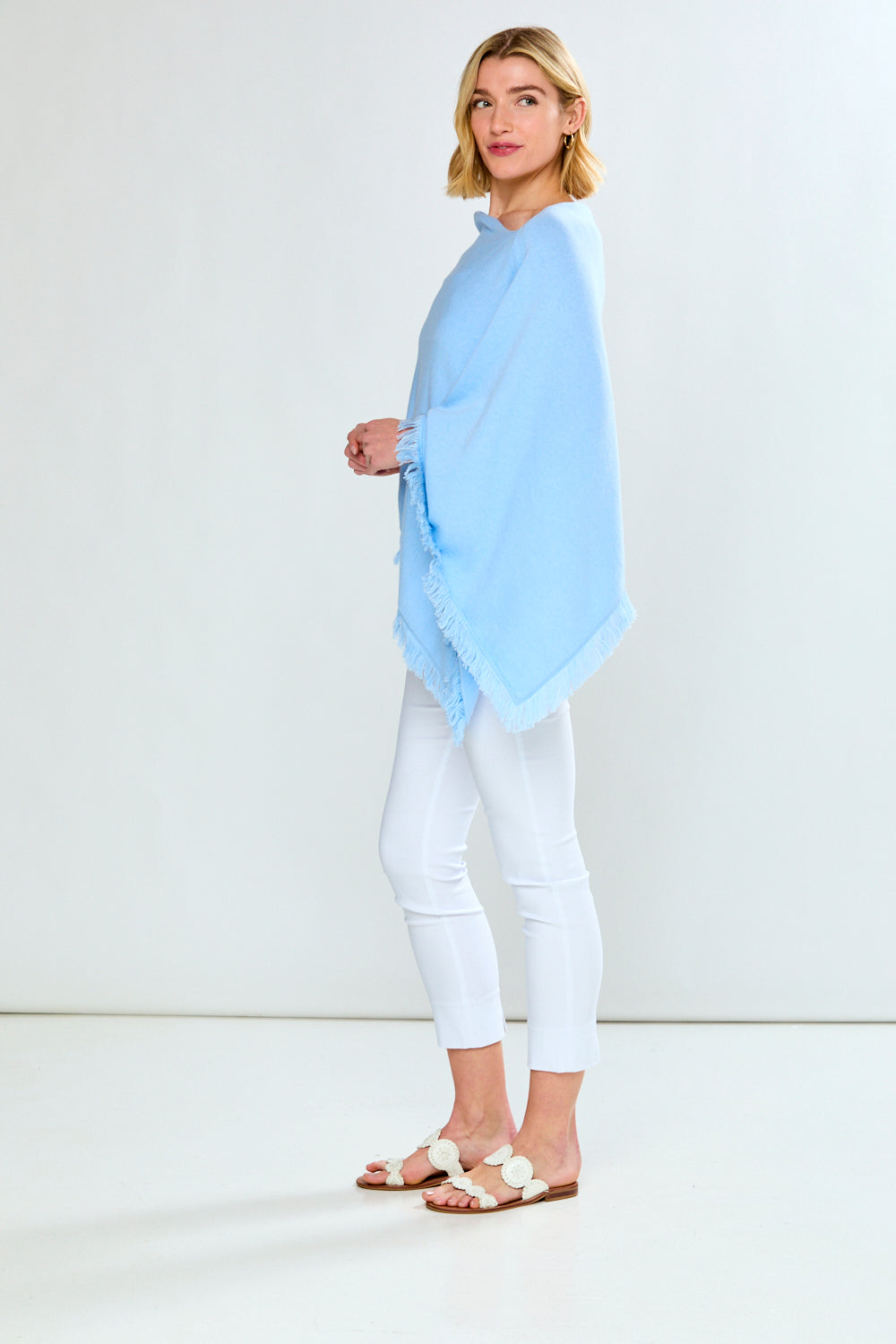 Woman wearing a light blue scarf and white pants against a white background