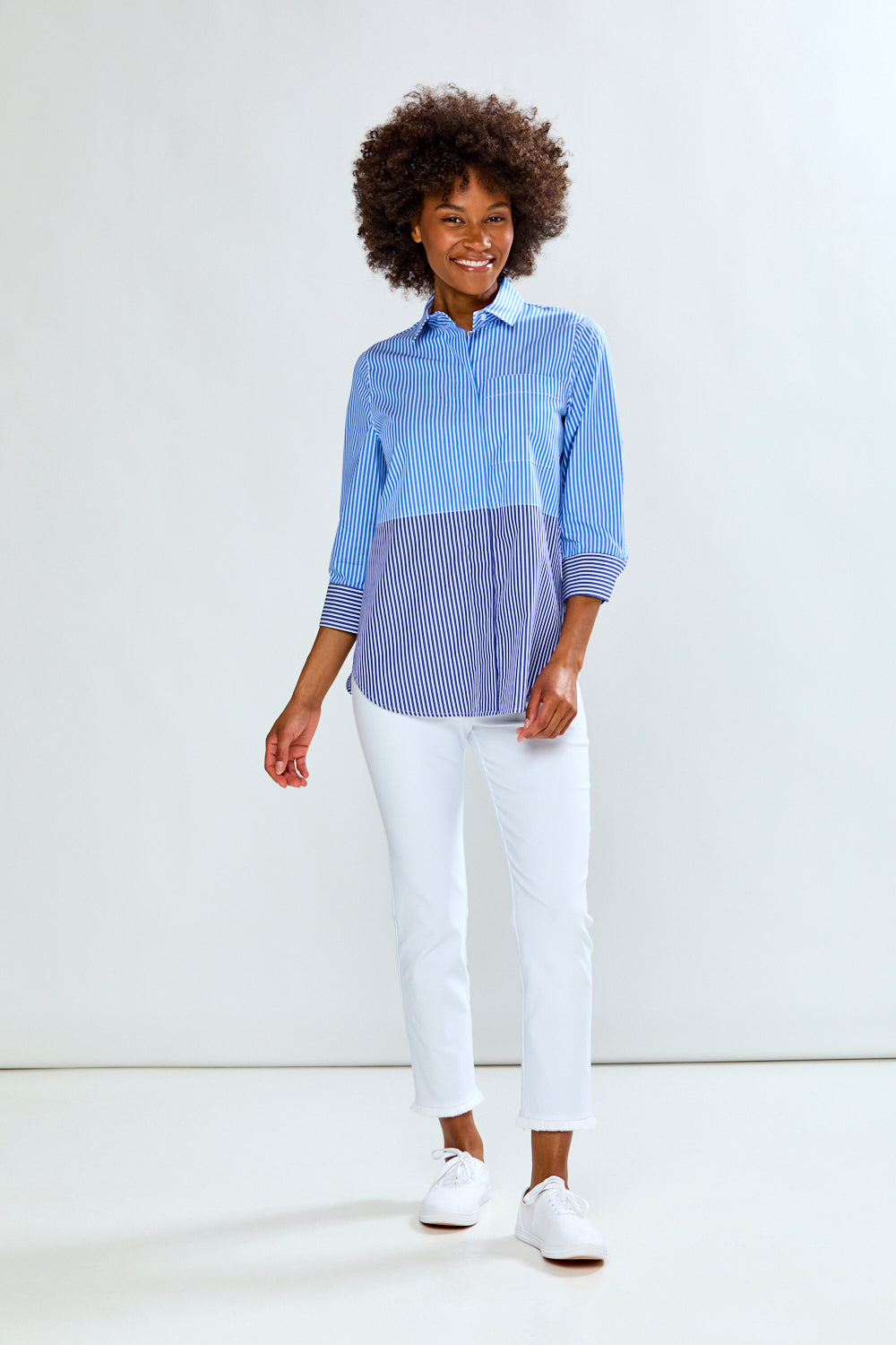 Person wearing a blue and white striped shirt with white pants on a white background