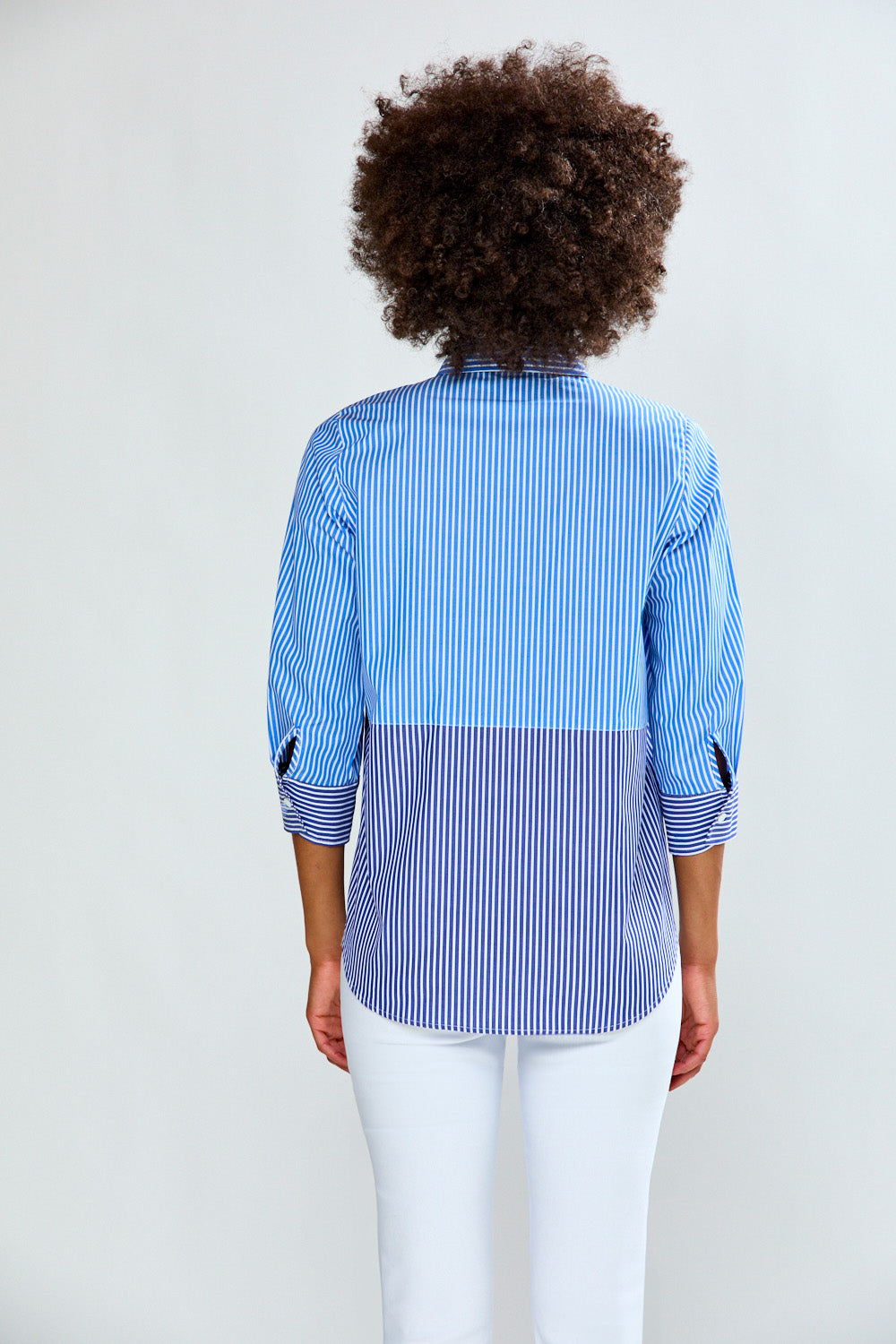 Person wearing a blue and white striped shirt with a color-blocked design on a plain background