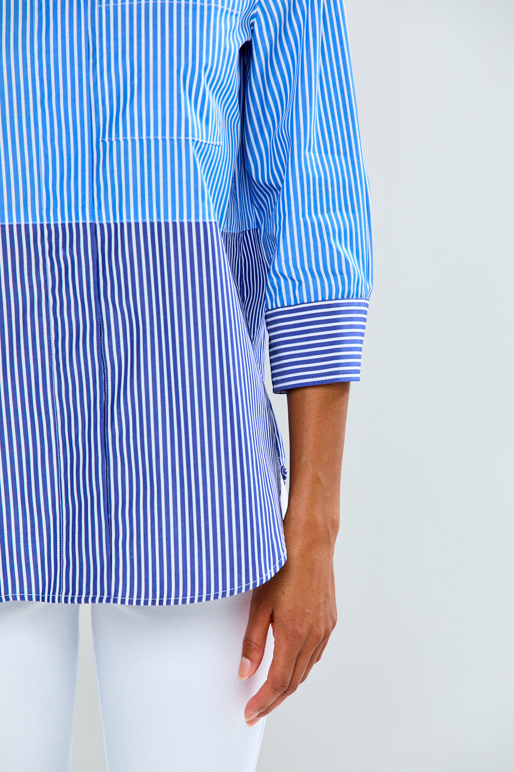 Blue and white striped shirt worn by a person on a light gray background