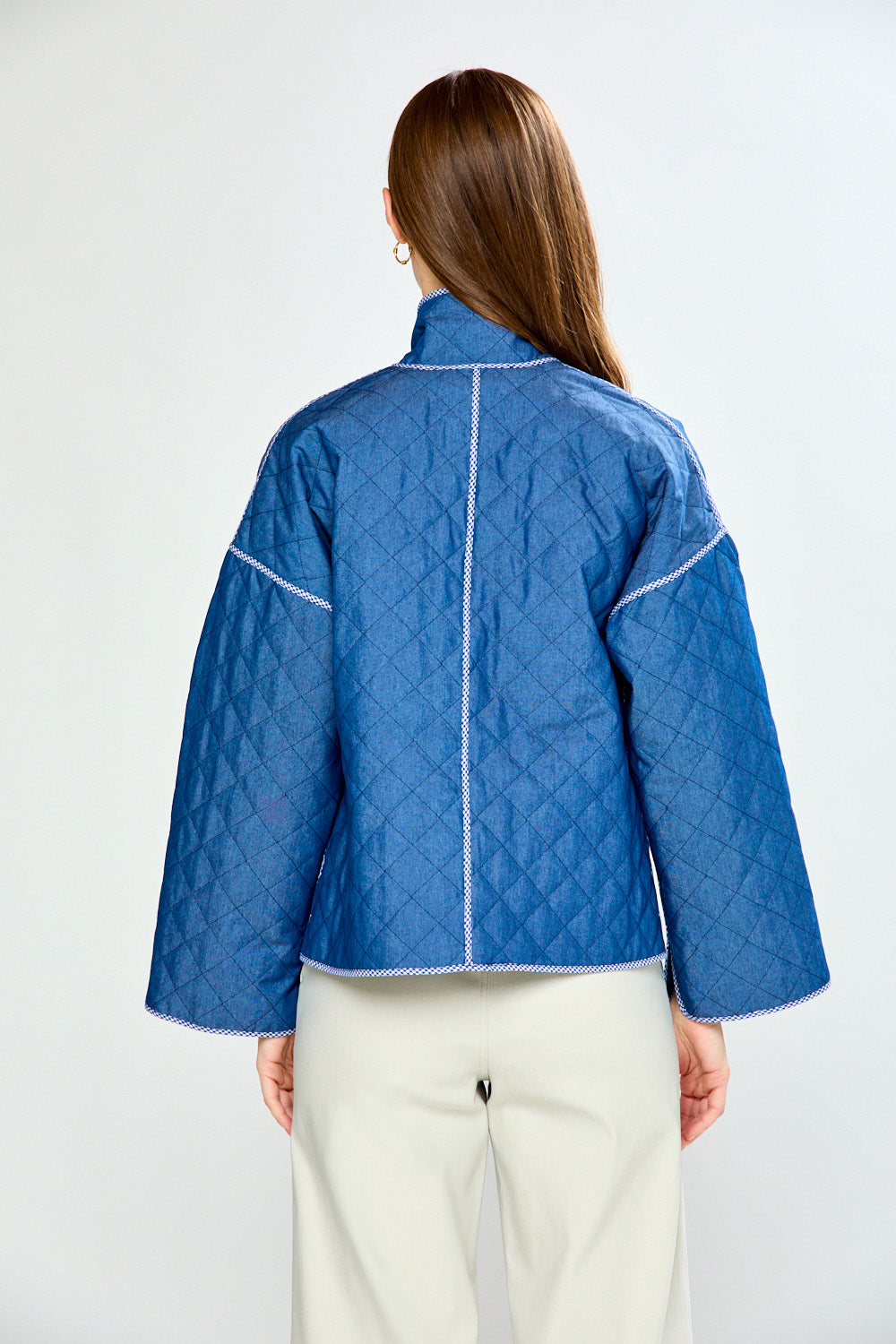 Person wearing a blue quilted jacket on a white background