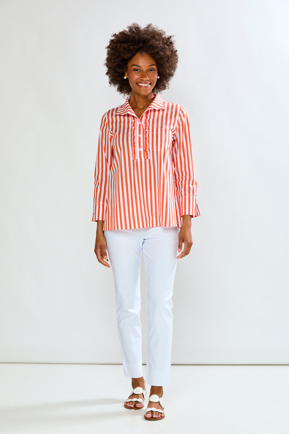 Woman wearing a red and white striped shirt and white pants against a white background