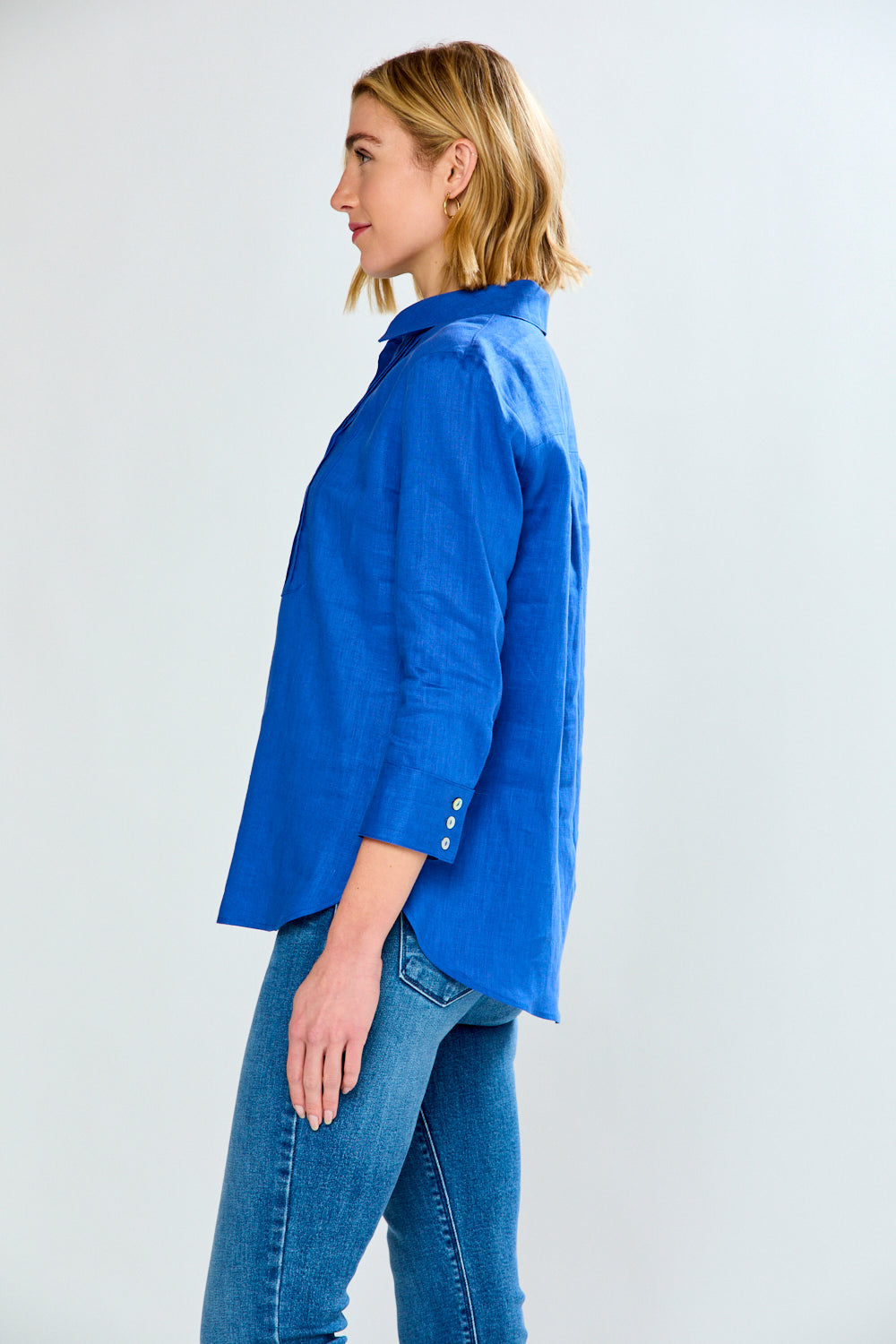 Woman wearing a blue shirt and jeans on a light gray background