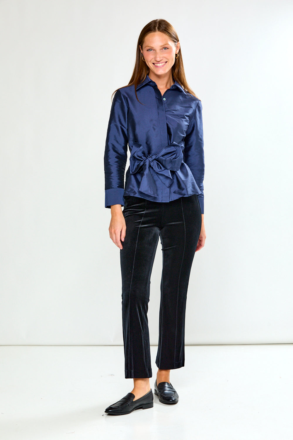 Woman wearing a blue blouse with a bow detail on a white background