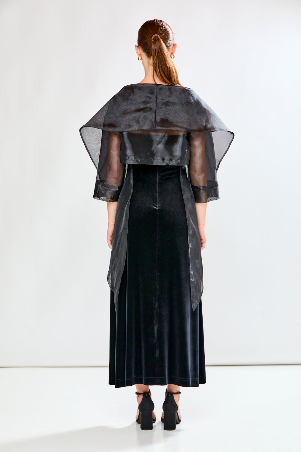 Woman wearing a black dress and black shawl against a white background