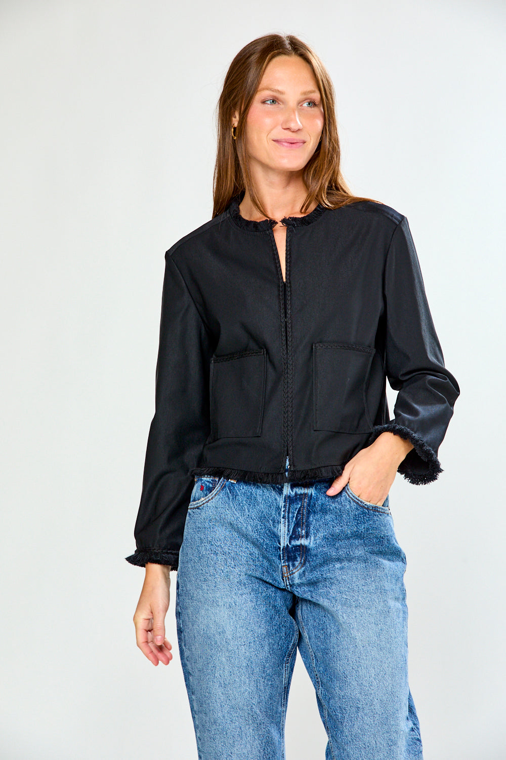 Woman wearing a black jacket and blue jeans on a white background