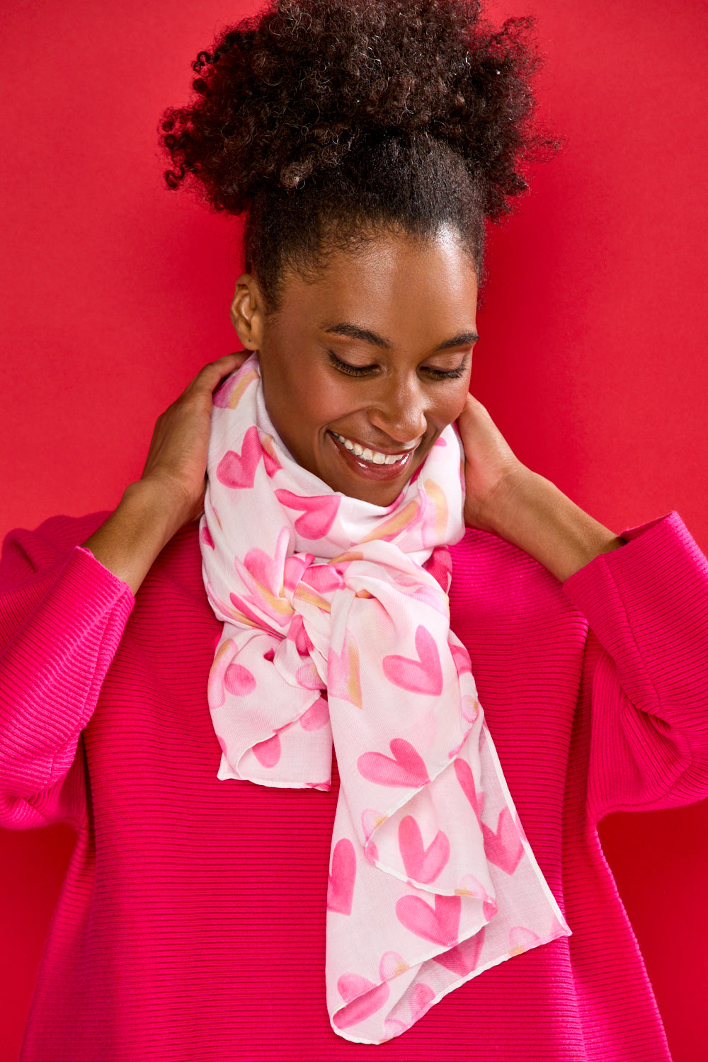 Woman wearing a pink heart-patterned scarf against a red background