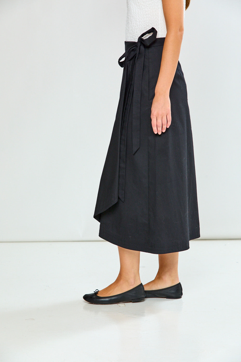 Person wearing a black wrap skirt on a white background