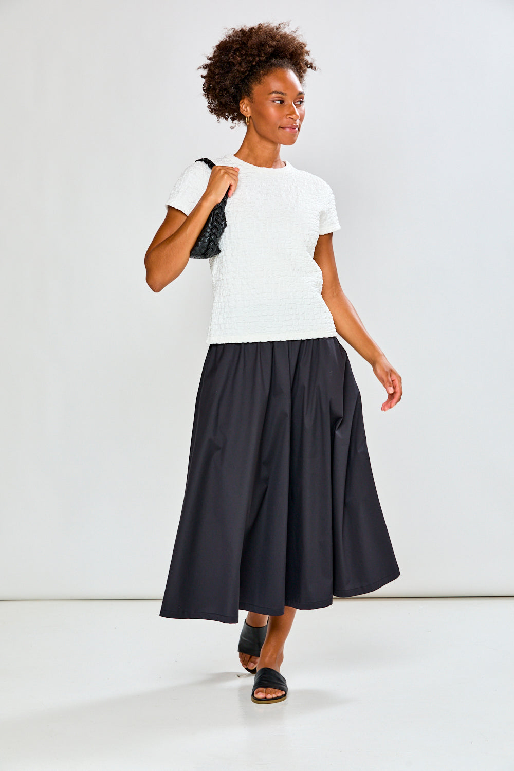 Woman wearing a white t-shirt and black skirt on a white background