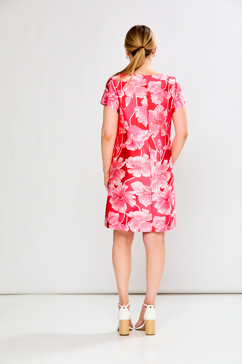 Woman wearing a pink floral dress against a white background