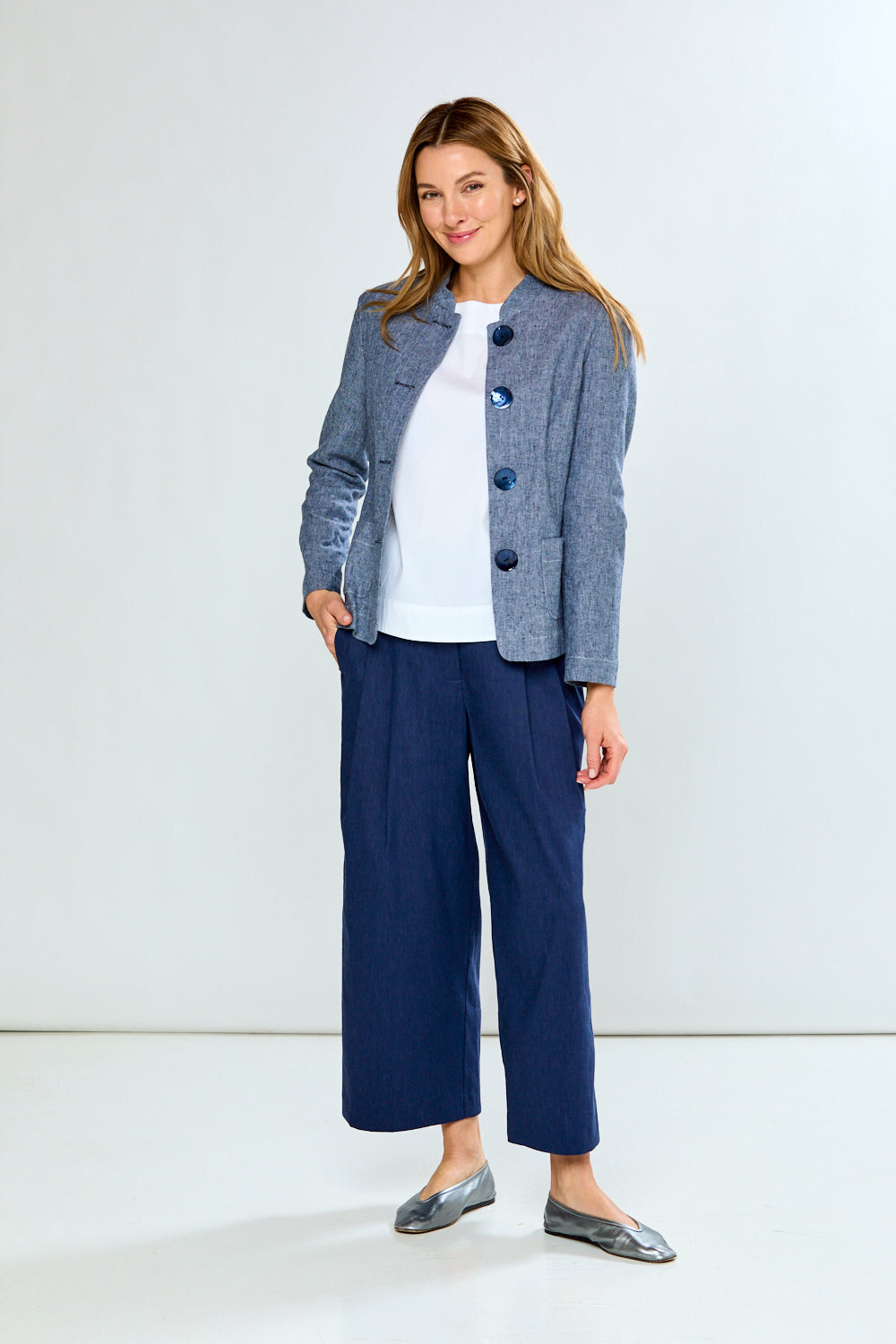 Woman wearing a blue checkered blazer and navy pants on a white background