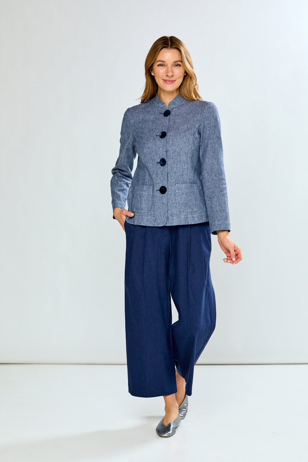 Woman wearing a blue checkered jacket and navy wide-leg pants on a white background