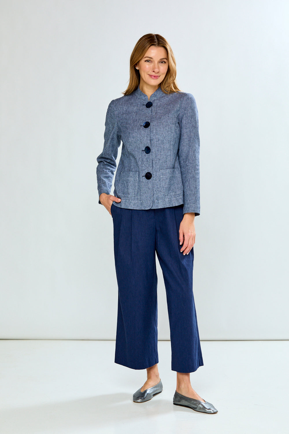 Woman wearing a blue checkered jacket and navy pants on a white background