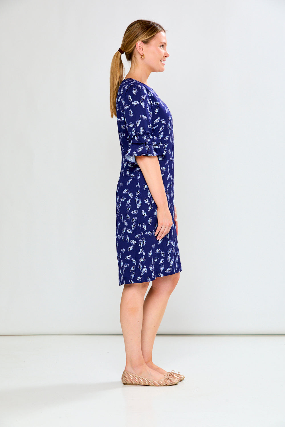 Woman wearing a blue dress with white floral pattern on a white background