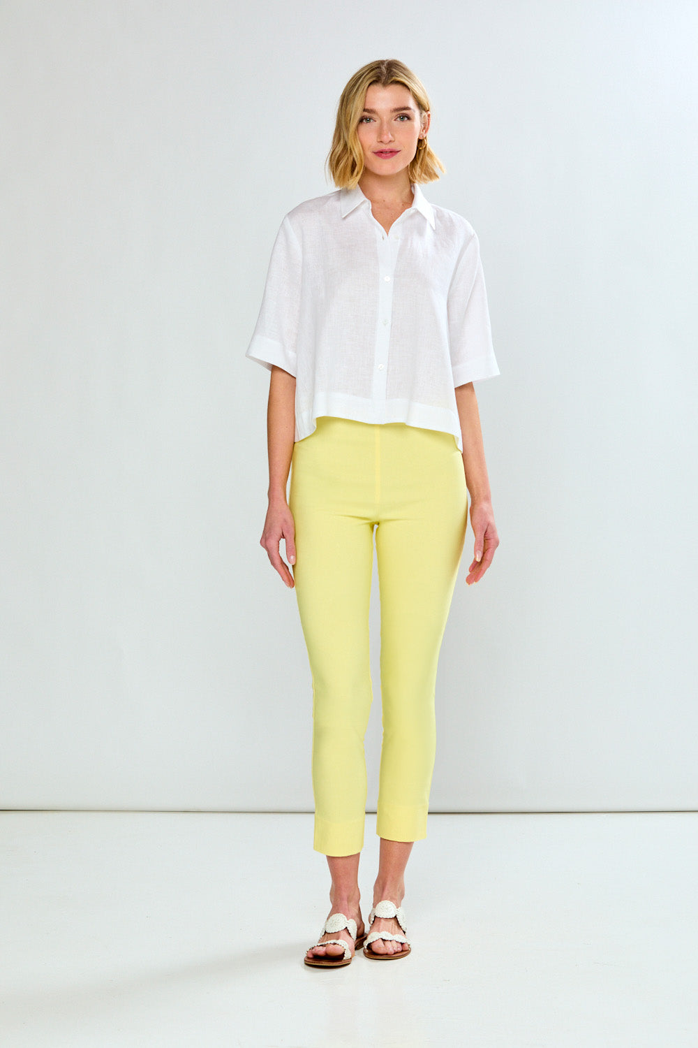 Woman wearing a white shirt and yellow pants against a white background