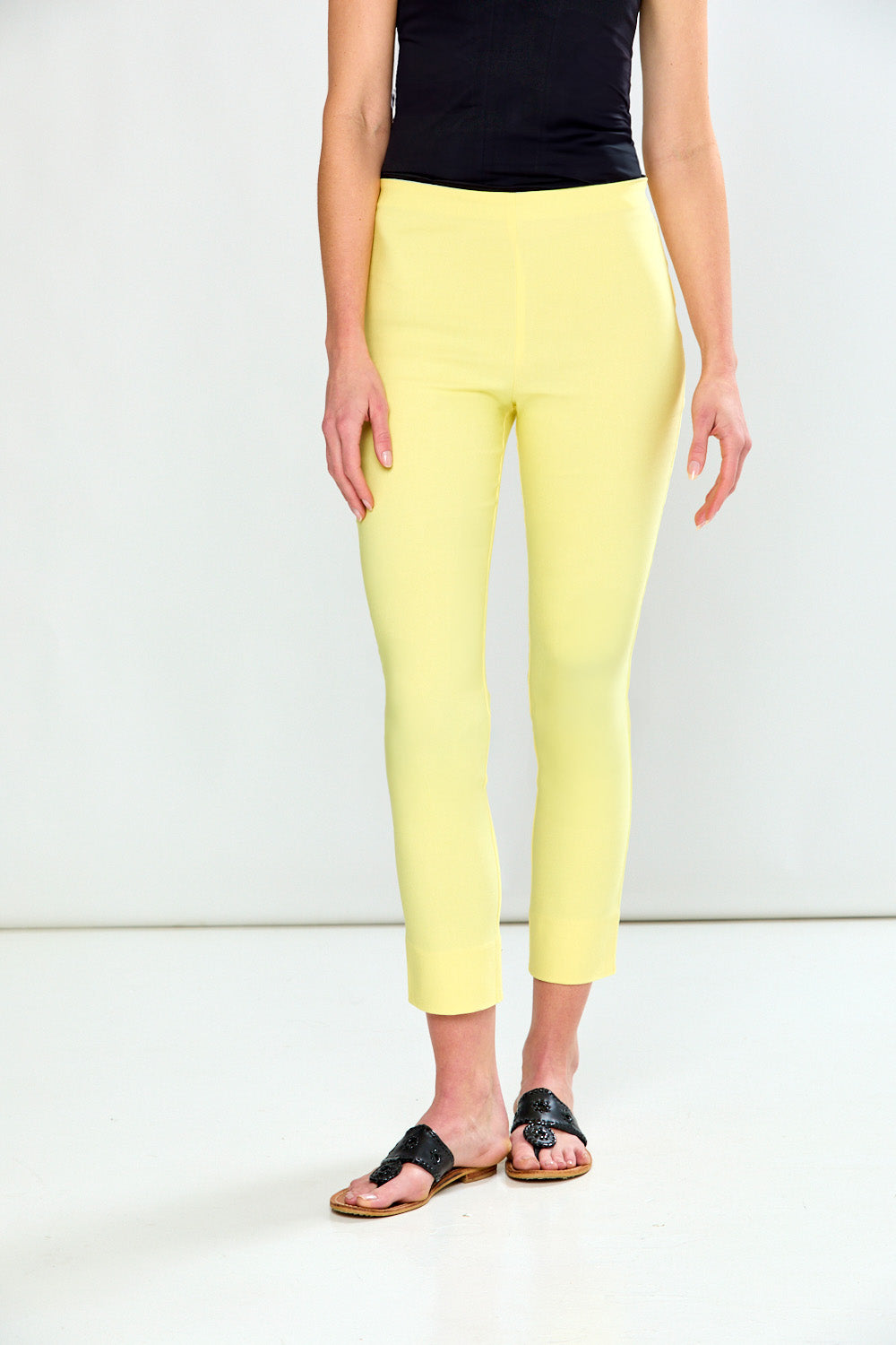 Person wearing yellow pants and black top on a white background