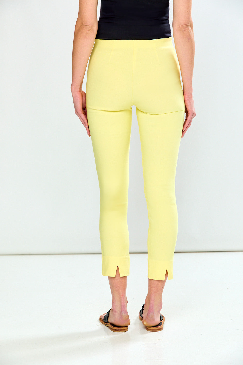 Person wearing yellow pants and a black top on a white background