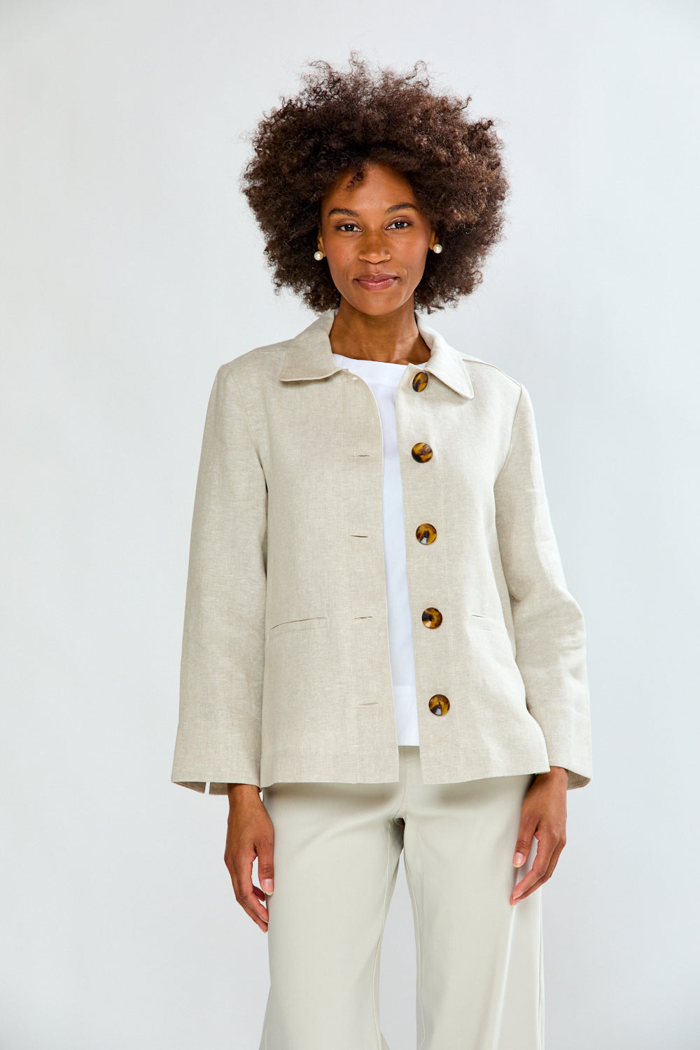 Woman wearing a beige suit with gold buttons on a white background