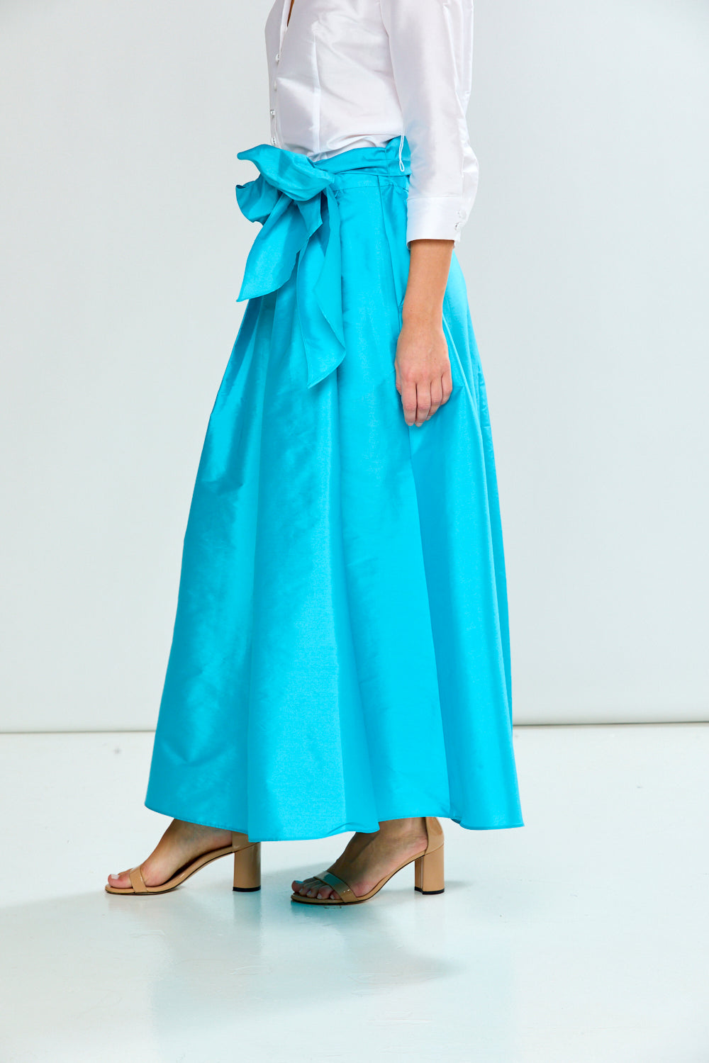 Person wearing a light blue skirt with a white top on a white background