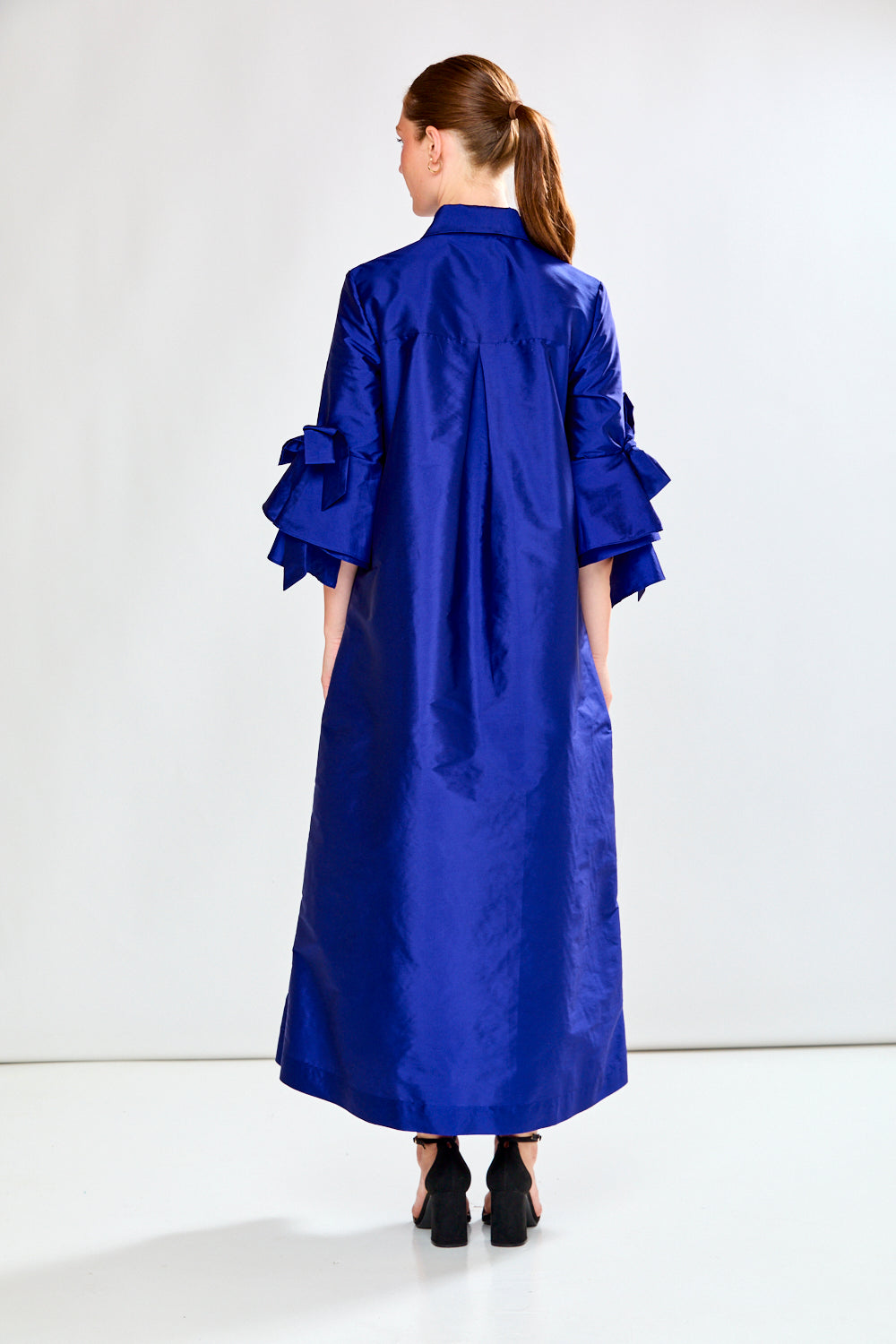 Woman wearing a long blue dress against a white background