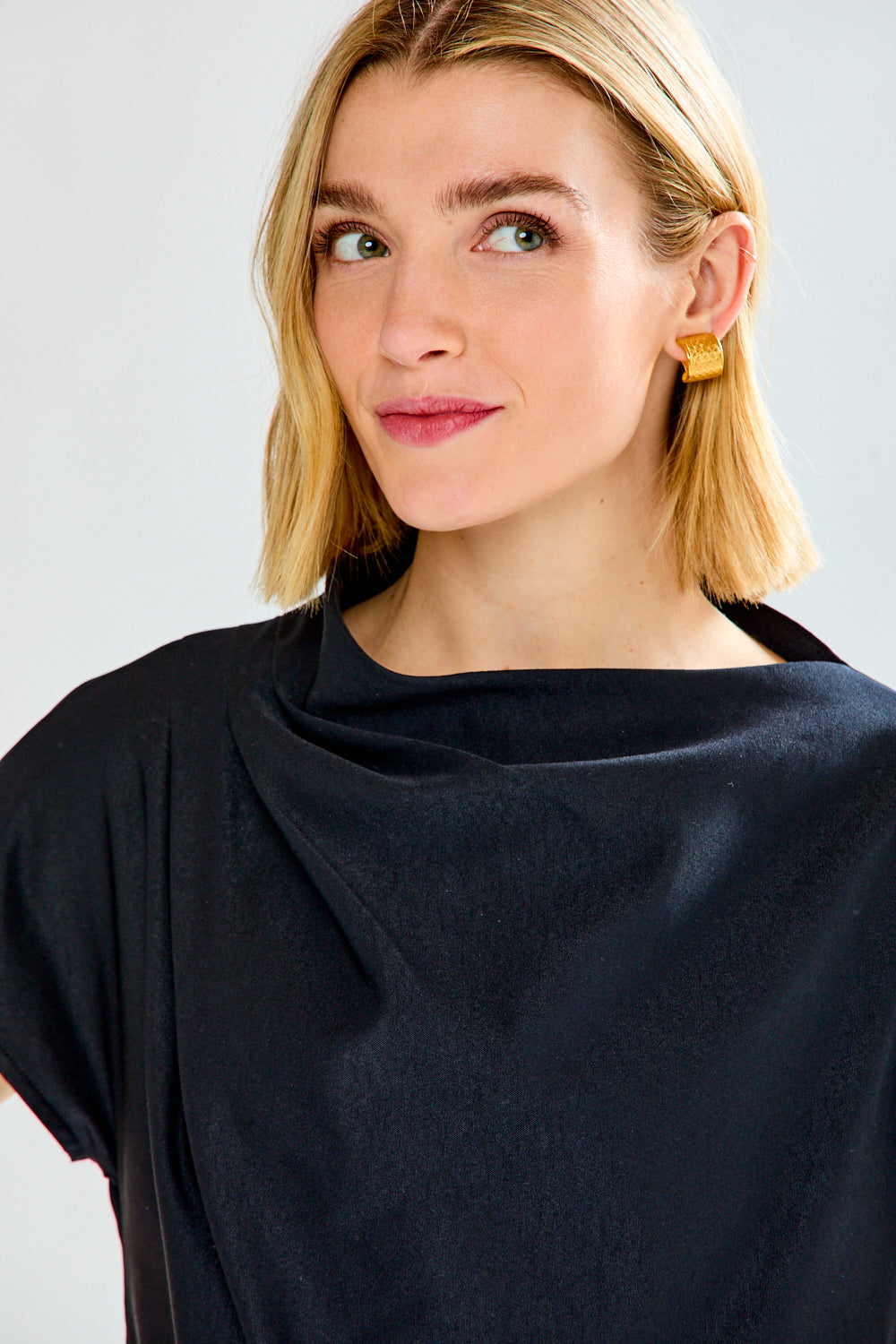 A woman shown from the back wearing a black short-sleeve top and leopard-print pants against a light gray studio background.