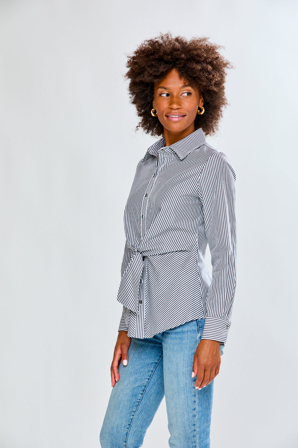 Woman wearing a striped shirt and jeans on a plain background