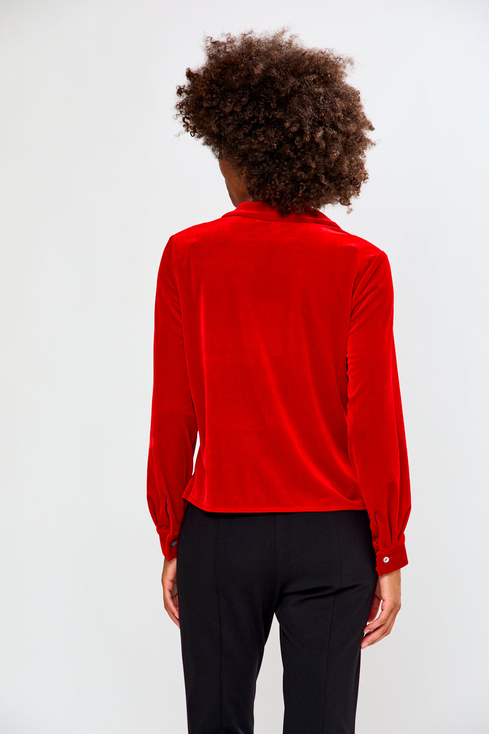 Person wearing a red blouse and black pants on a white background