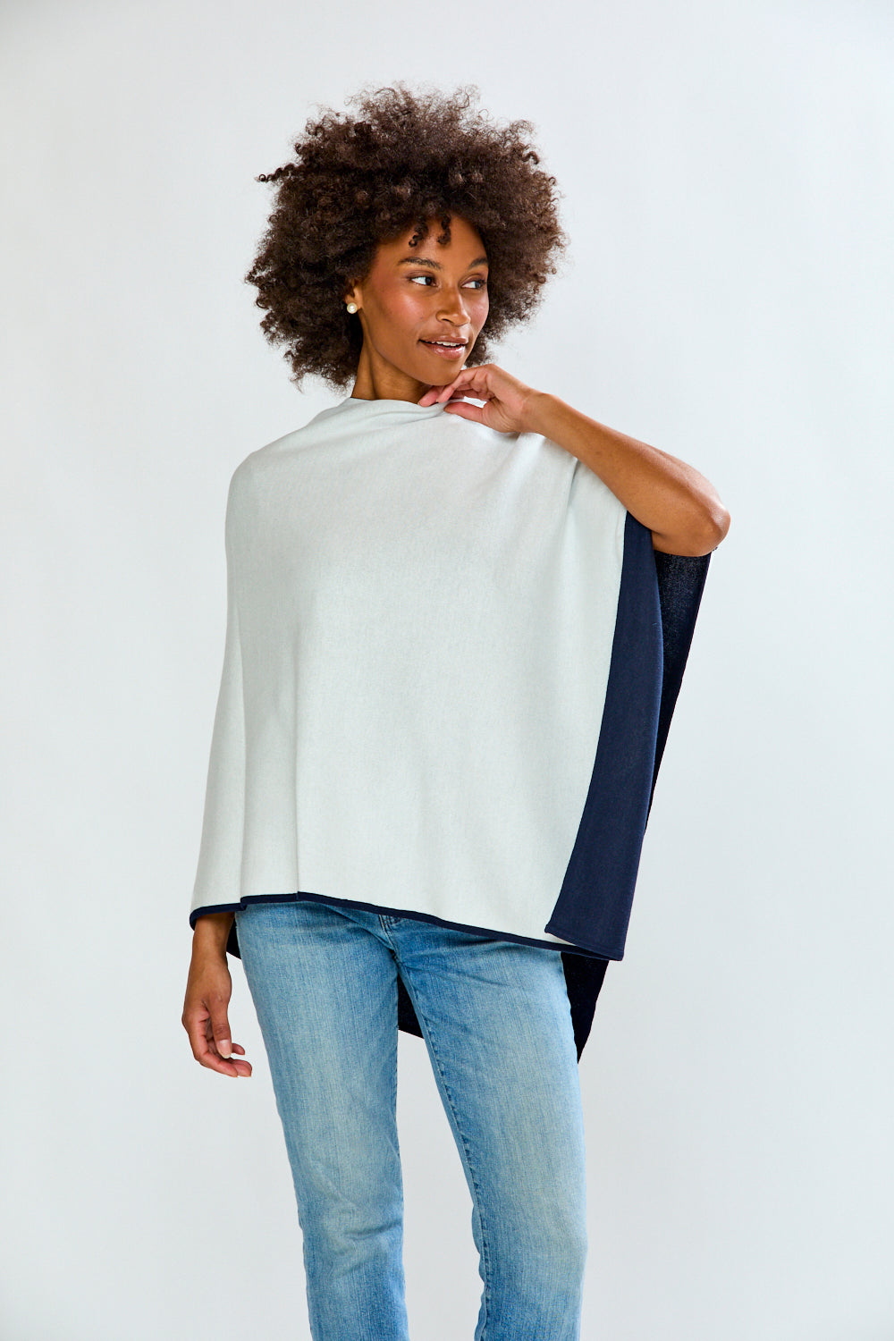 Woman wearing a white and navy top with blue jeans on a white background