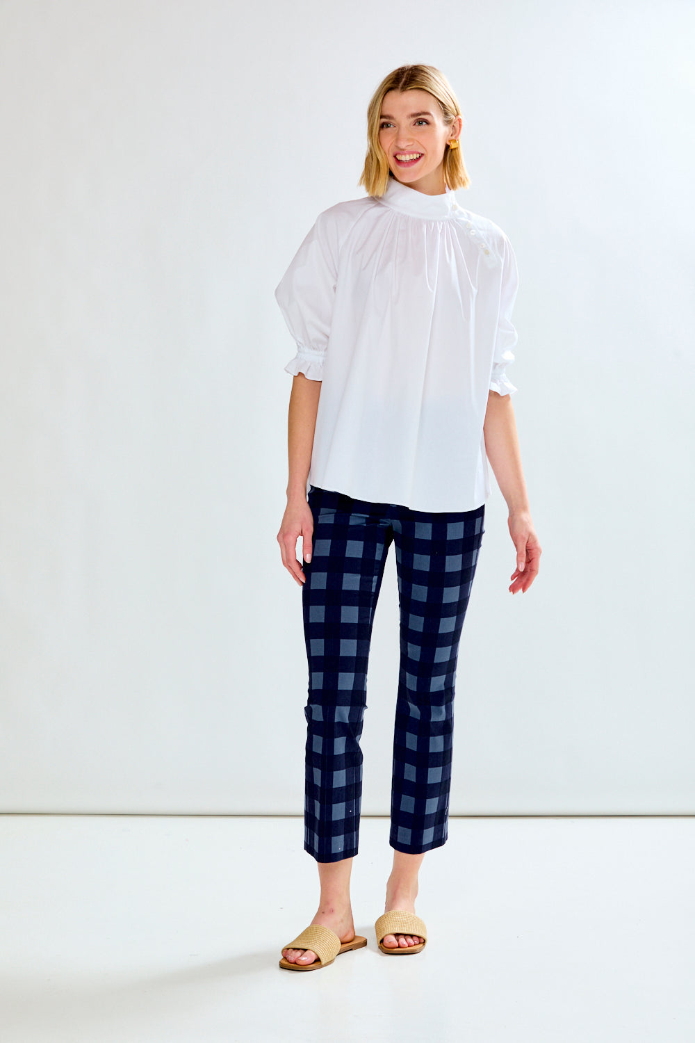 Woman wearing a white blouse and blue plaid pants on a white background