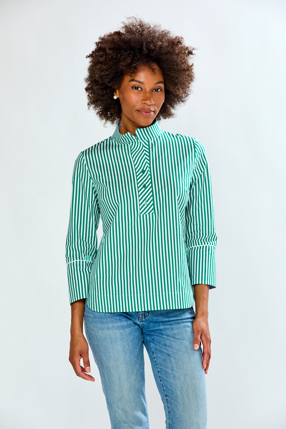 Woman wearing a green and white striped shirt and blue jeans on a white background