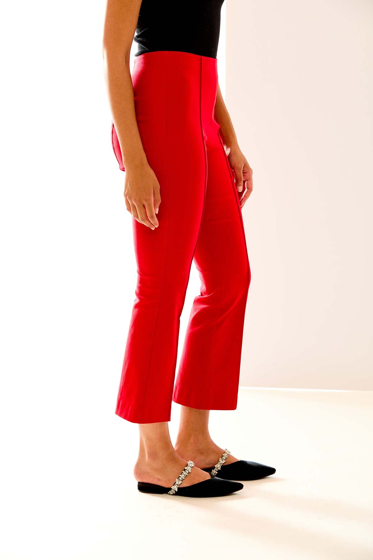 Person wearing red pants and black shoes on a white background