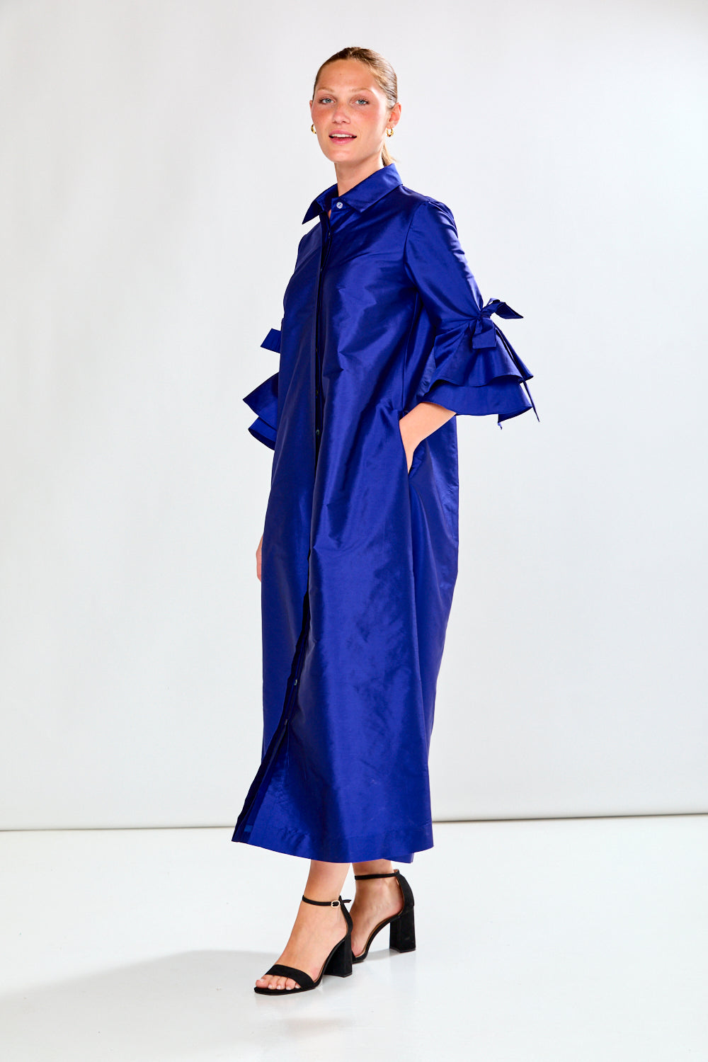 Woman wearing a long blue dress against a white background