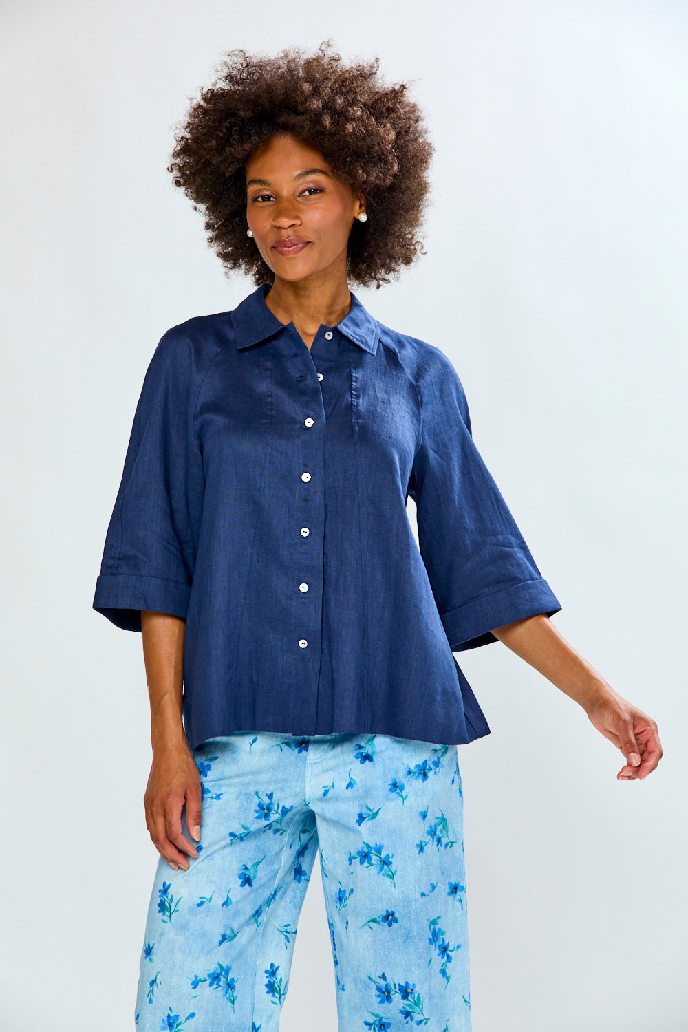 Woman wearing a blue shirt and light blue floral pants on a white background
