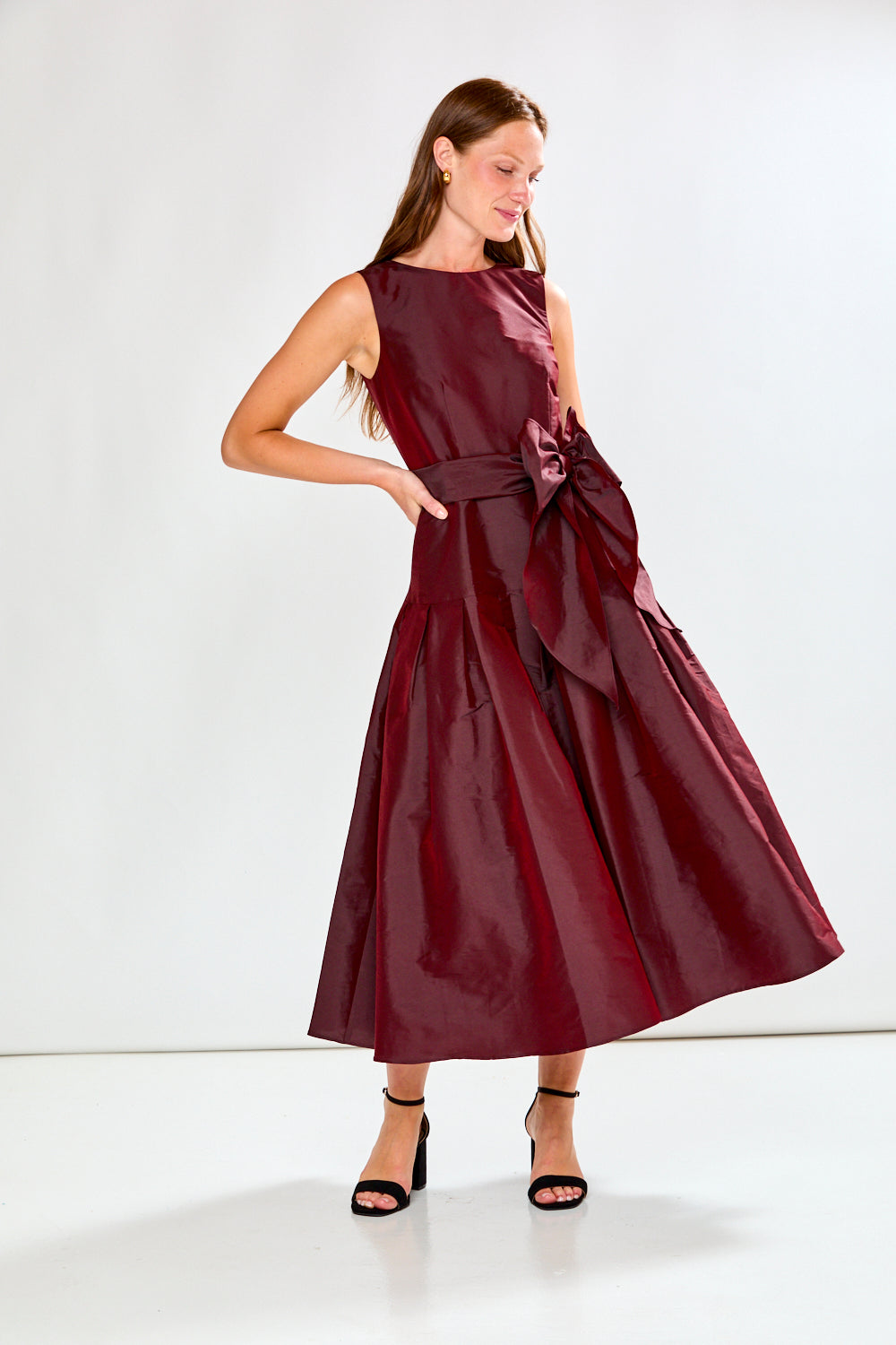 Woman wearing a burgundy dress with a belt on a white background