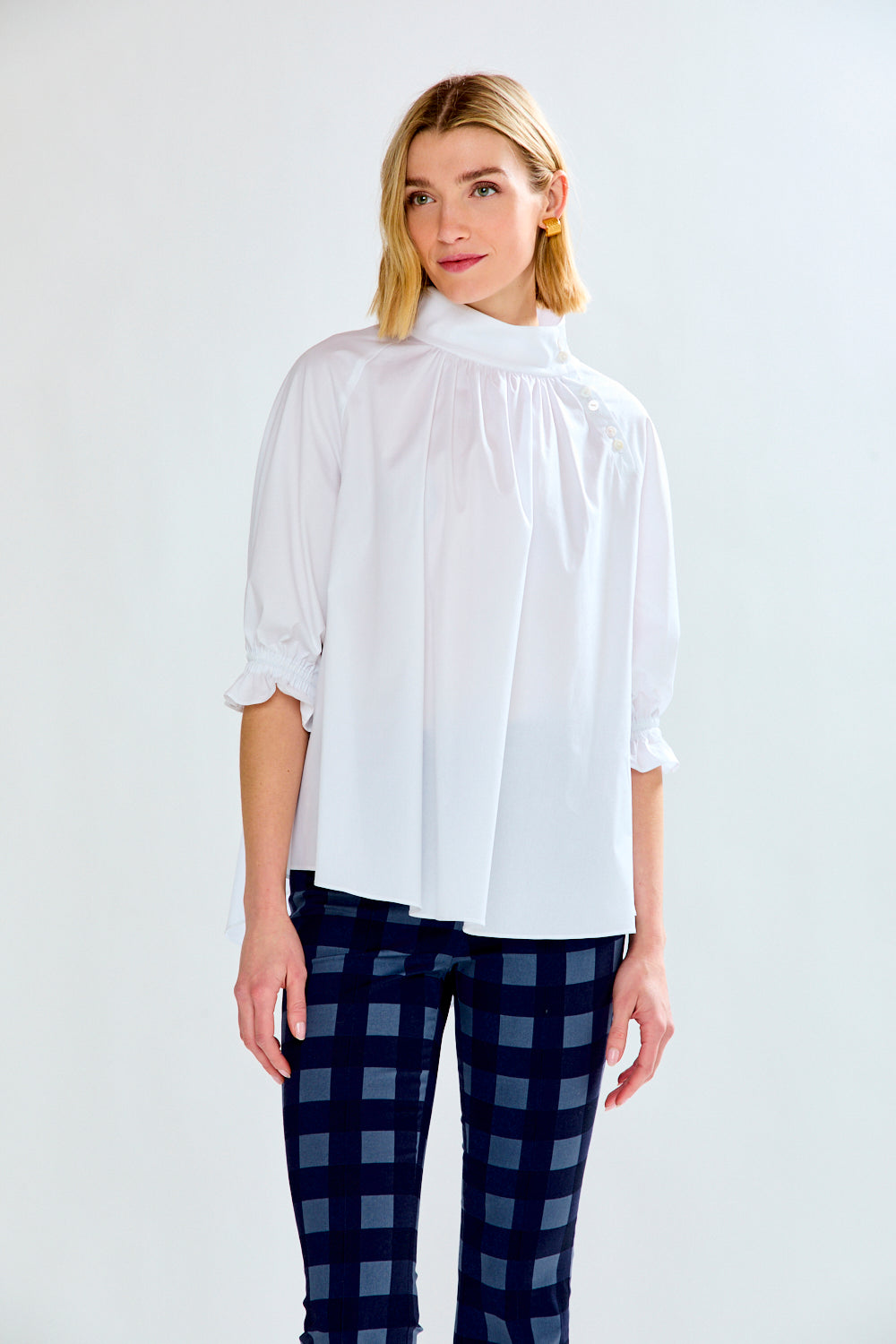 Woman wearing a white blouse and blue checkered pants on a white background