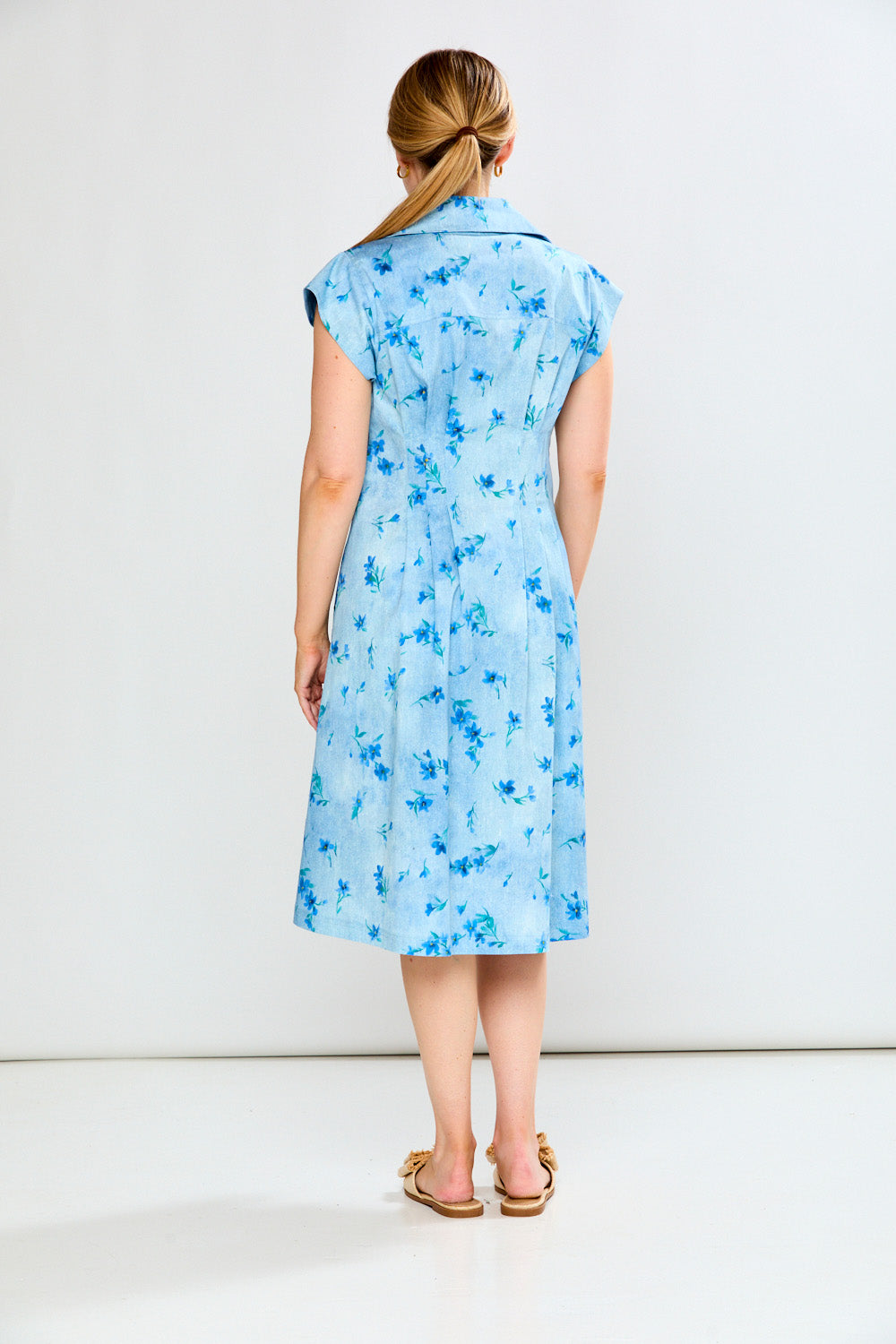 Woman wearing a blue floral dress against a white background