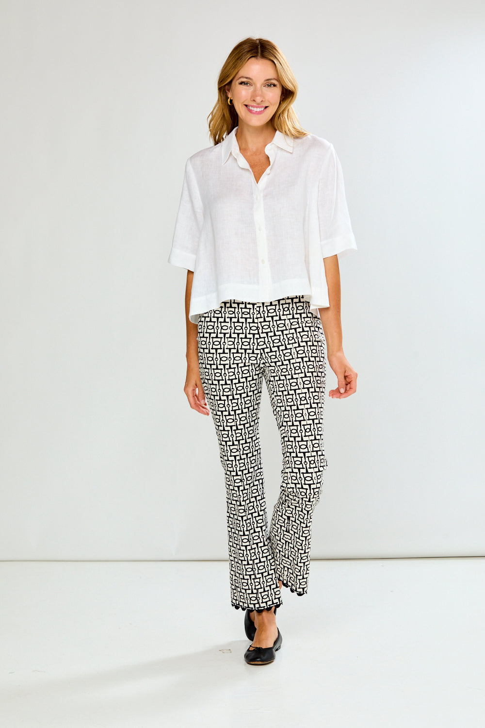 Woman wearing a white blouse and patterned pants on a white background