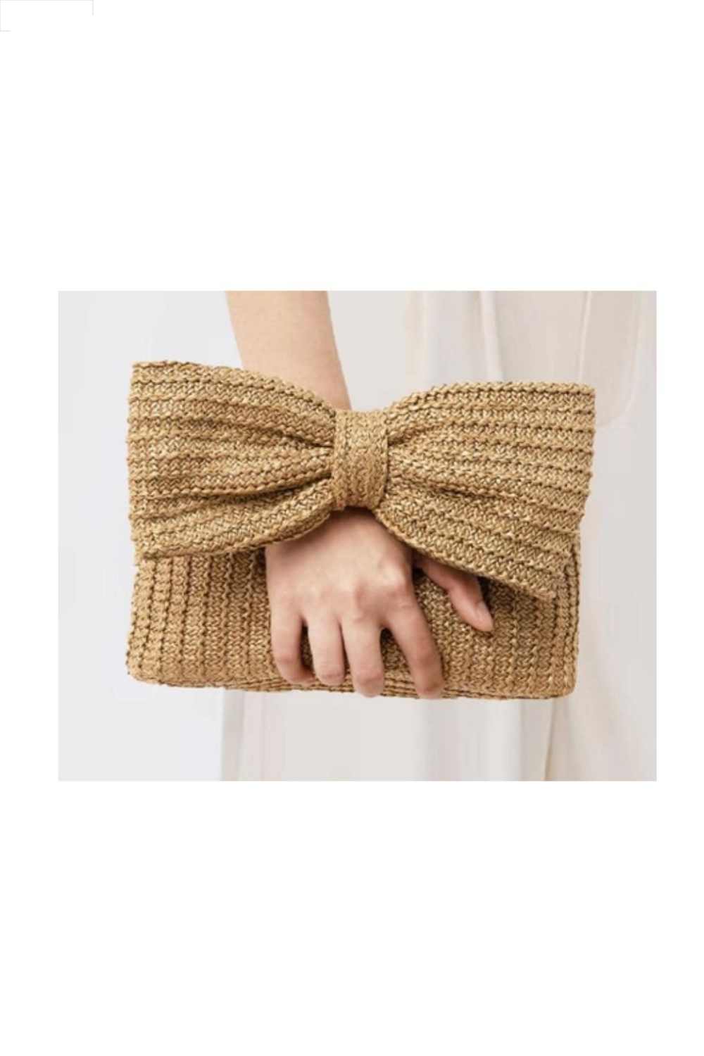 Hand holding a woven clutch with a large bow on a white background