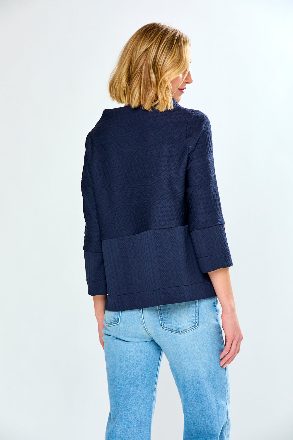 Woman wearing a navy blue jacket and light blue jeans on a white background