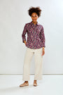 Woman wearing a patterned shirt and white pants on a white background