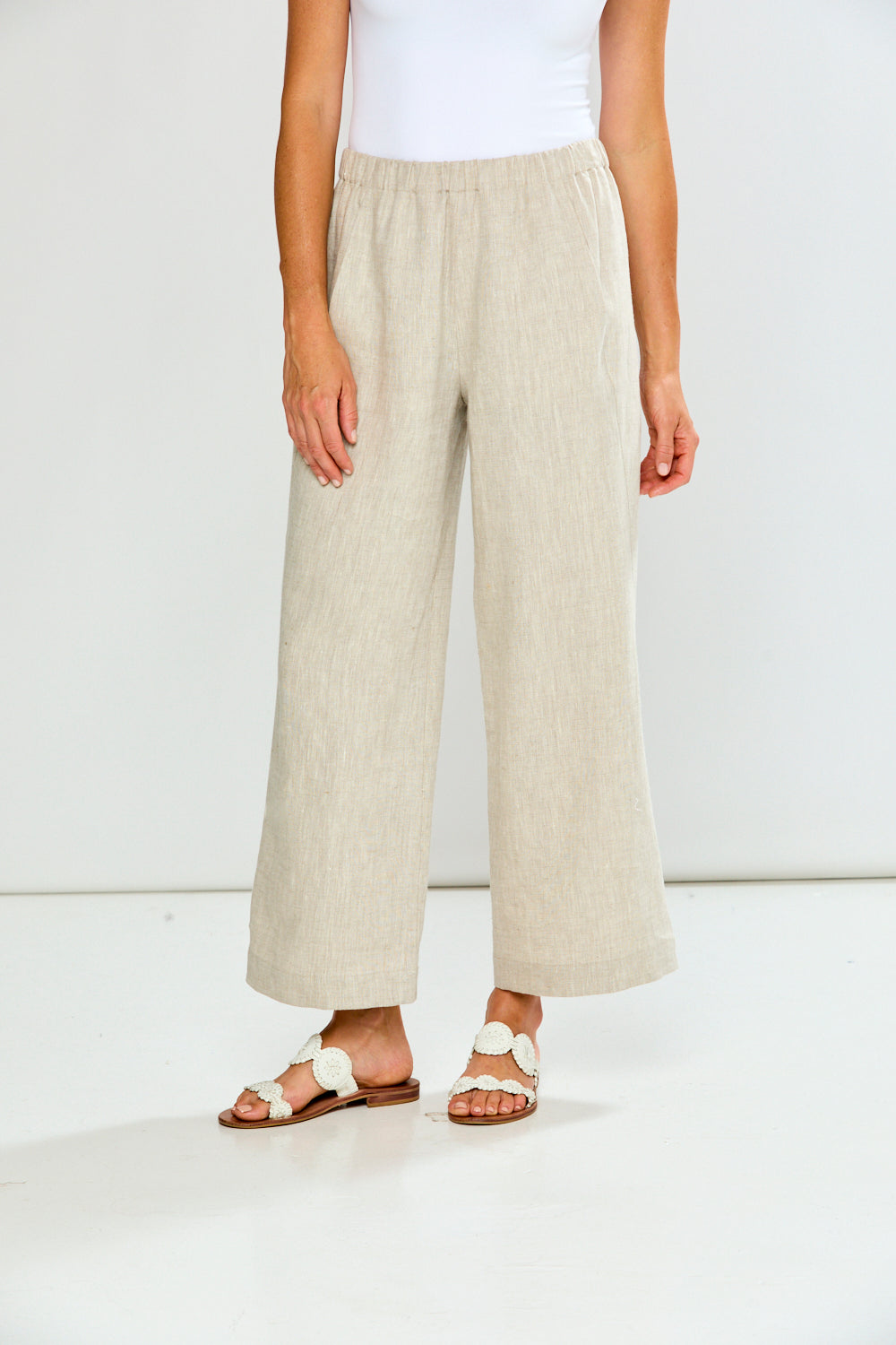 Person wearing beige wide-leg pants on a white background